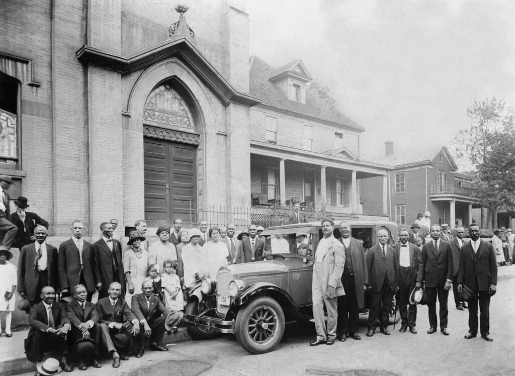 A large group of congregants and a nice car out front of High Street Baptsist.