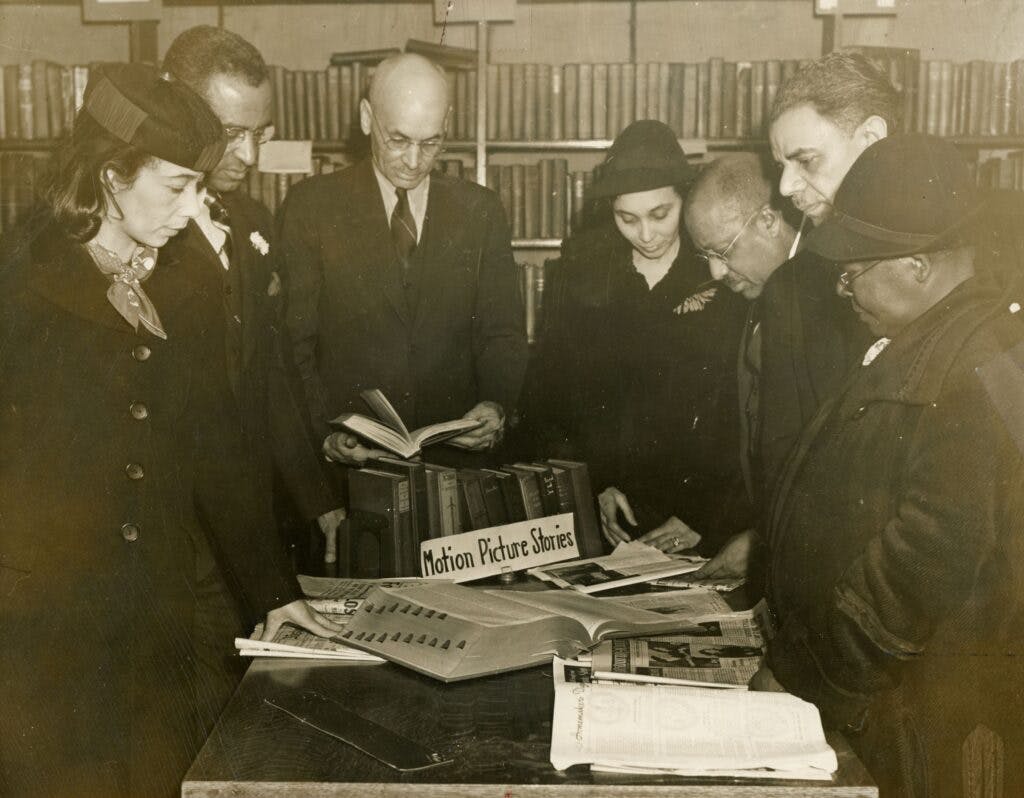 Photo of the first patrons to register at the Library, standing around a table filled with reading materials.