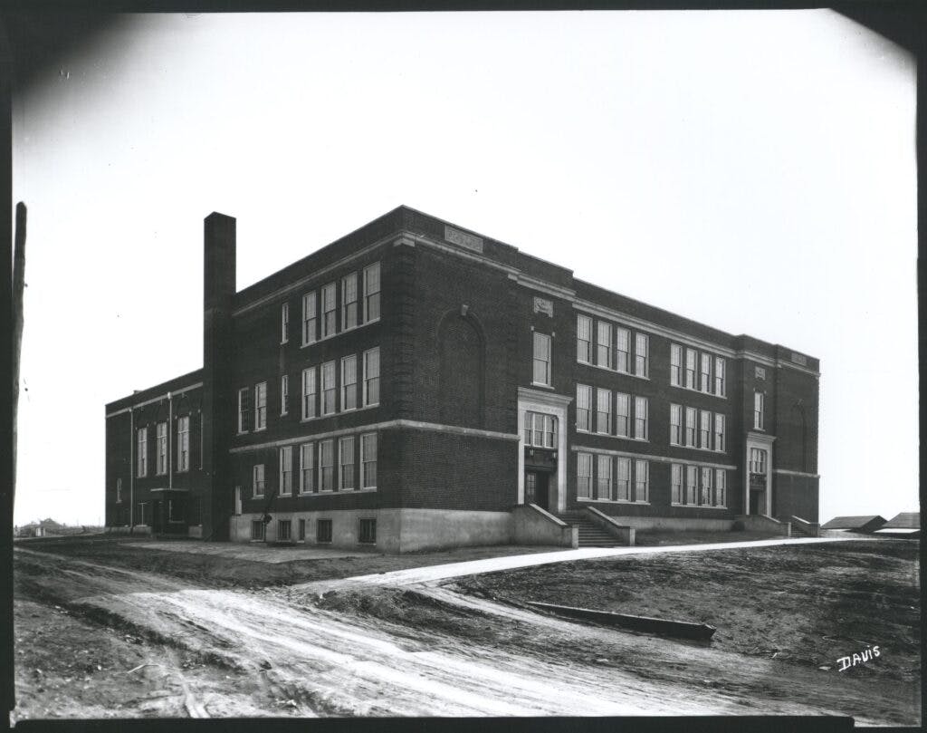 A black and white photo of the old Lucy Addison High School. Largely rectangular and surrounded by dirt road due to the photo being taken shortly after construction.