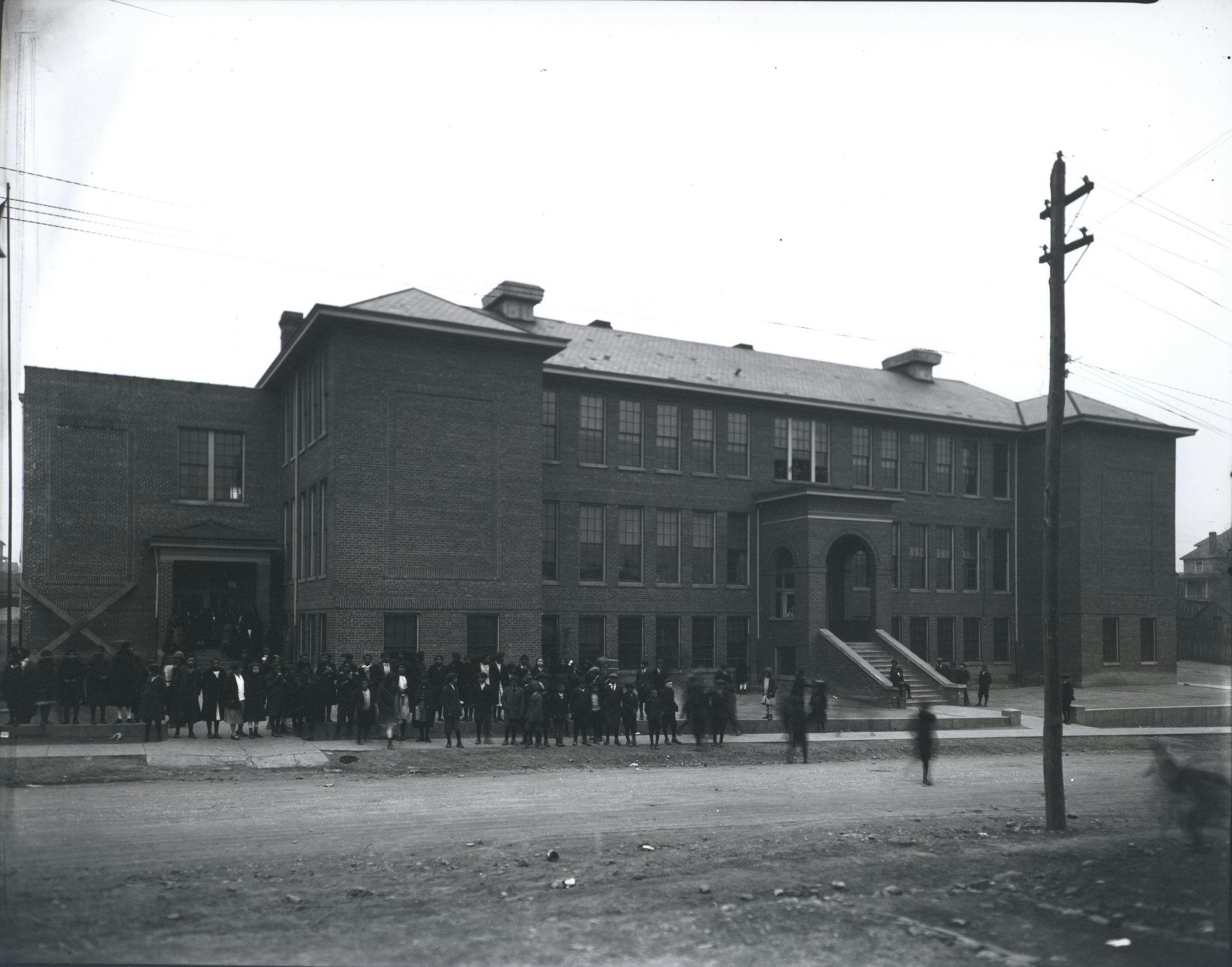 The Harrison school with its large student body out front. The building was 3 main stories tall with a large arched entrance