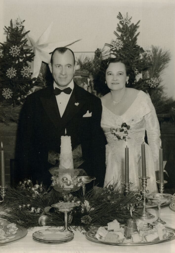 Dr. Downing and his wife in tuxedo and dress with a fancy table decorated in front of them