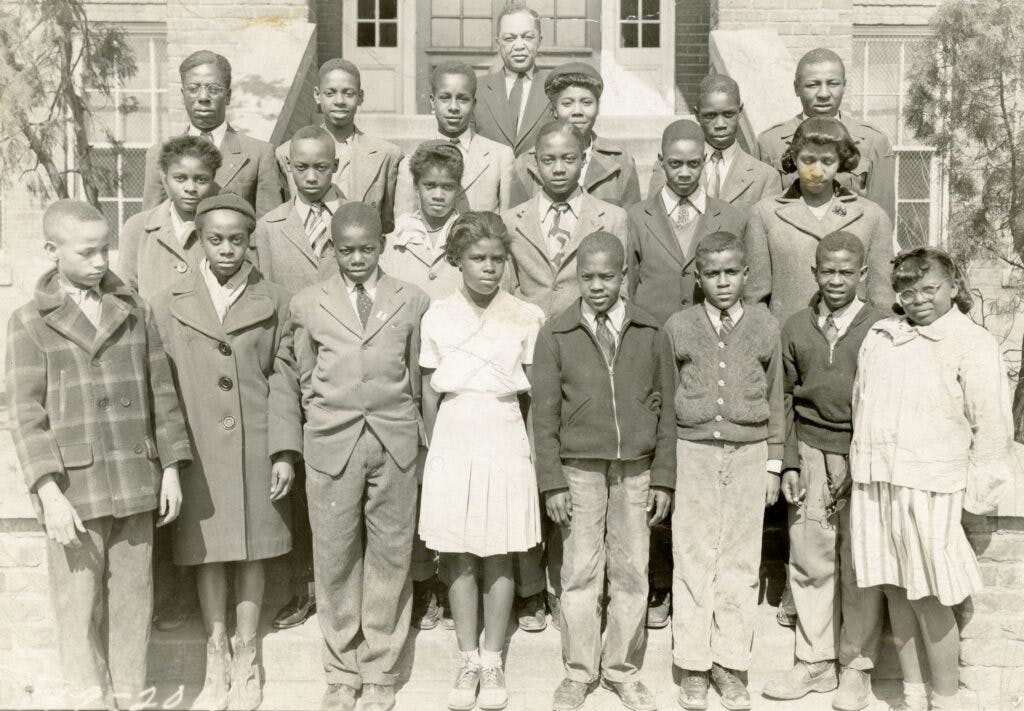 A group of African American students, most in peacoats, pose for a picture